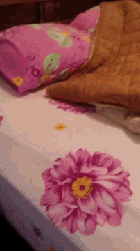 a bed with pink flowers on it and a pillow that says i love you