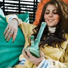 a woman is laying on a bean bag chair holding a bong .
