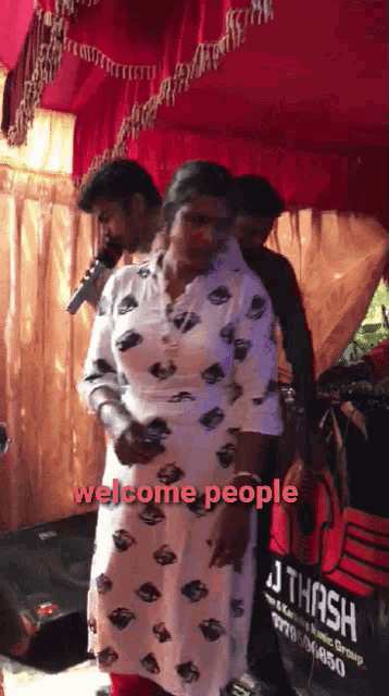 a woman stands in front of a sign that says " welcome people "