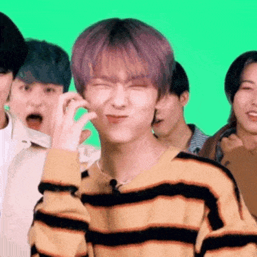 a young man with purple hair is making a funny face while standing in front of a green screen .