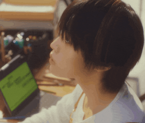 a woman sitting at a desk looking at a laptop screen