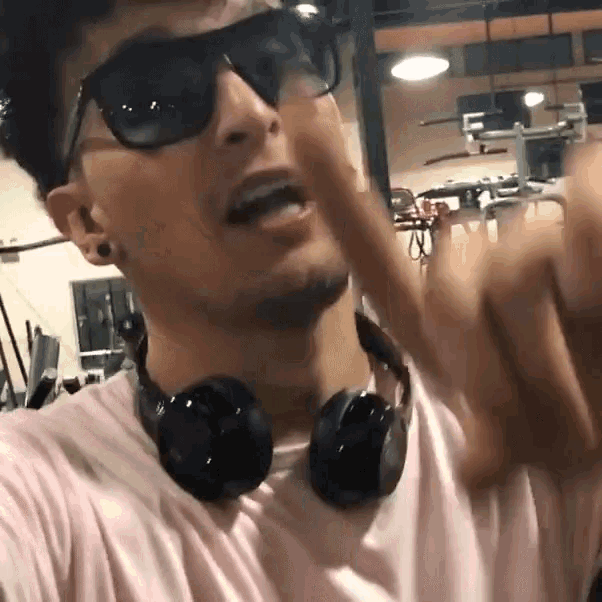 a man wearing sunglasses and headphones is giving a middle finger