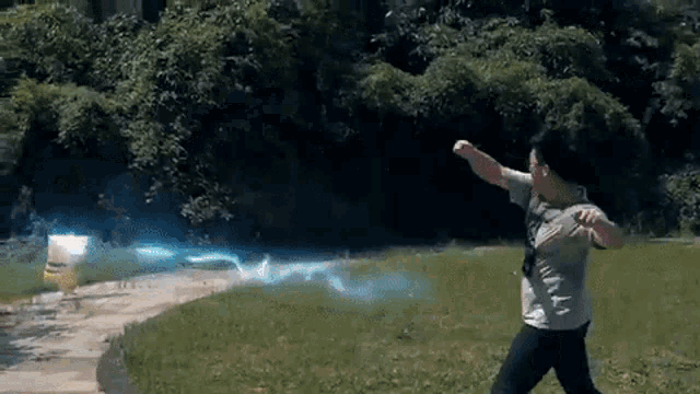 a person is throwing a frisbee in a field with a blue light coming out of it .