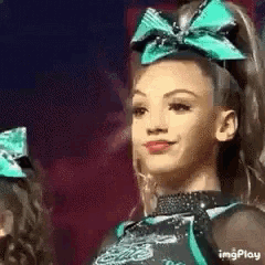 a cheerleader with a bow on her head is smiling .