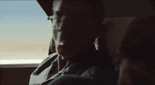 a man wearing glasses looks out a window