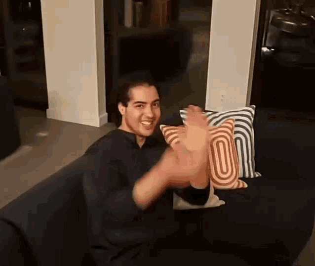 a man is sitting on a couch with his hands in the air