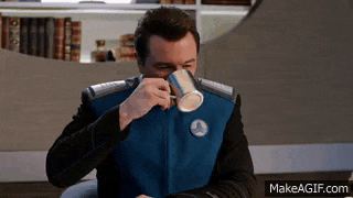 a man in a space suit is drinking from a coffee mug .