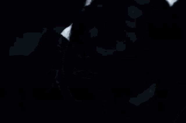 a person with a ring on their finger is covering their face with their hands in a dark room .