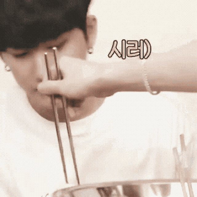 a man is eating noodles with chopsticks while wearing a bracelet .