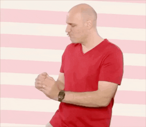 a man in a red shirt is standing in front of a pink and white striped wall .