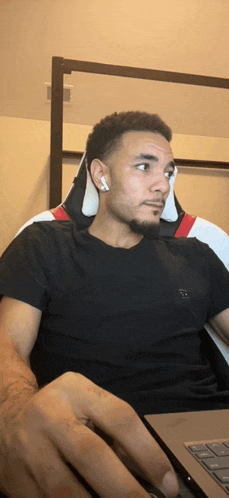 a man wearing ear buds is using a laptop computer