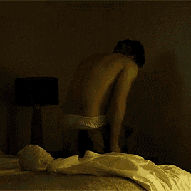 a man without a shirt is taking off his shirt in a dark room