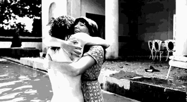 two women are hugging each other in front of a pool .