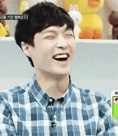 a man in a plaid shirt is smiling with his eyes closed