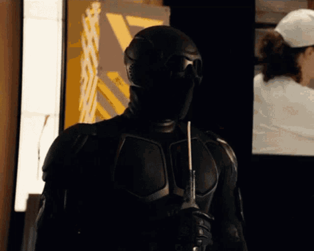 a man in a black suit holding a stick