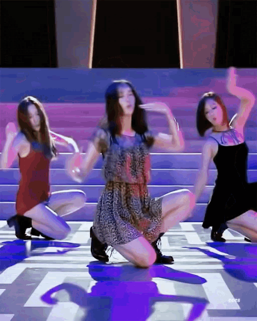 a woman in a leopard print dress is kneeling down on the floor while two other women dance .