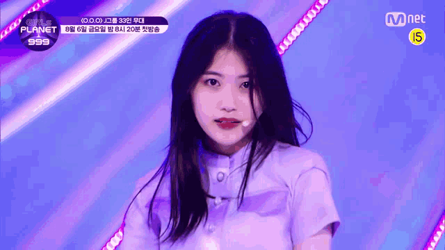 a girl in a purple shirt is singing into a microphone on a stage .