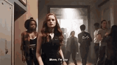 a woman is walking down a hallway with a group of people and talking .