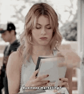 a woman is holding a piece of paper in her hand and asking , `` business marketing ? ''
