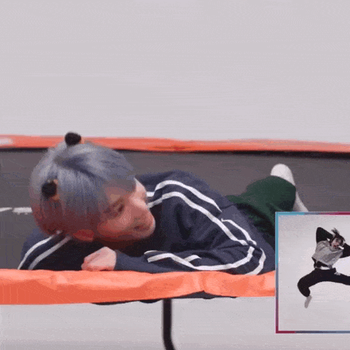 a person is laying on a trampoline with a picture of a person jumping in the background