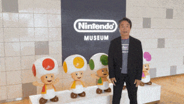 a man in a suit stands in front of a nintendo museum sign