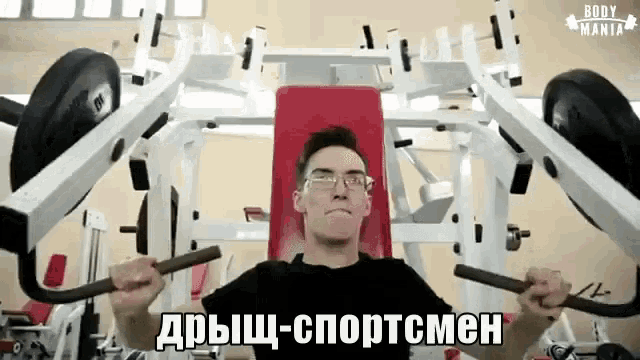 a man wearing glasses is using a machine in a gym with the words body mania written on the bottom