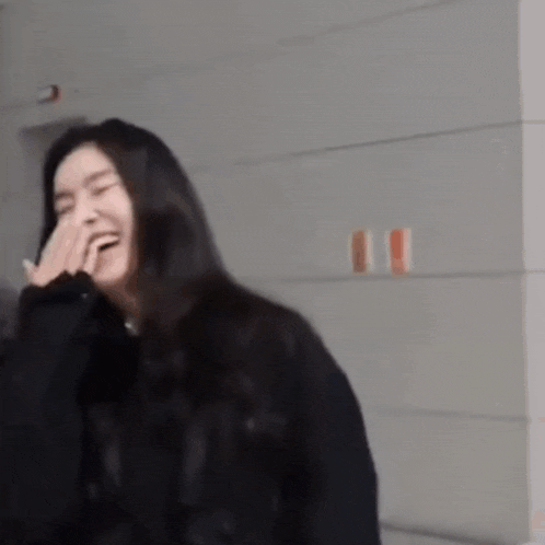 a woman is laughing with her hand on her face .