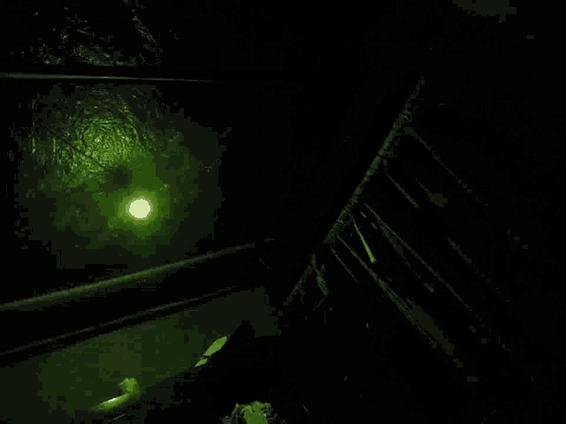 a dark room with a green light shining on the ceiling