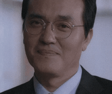 a man wearing glasses and a suit is smiling and looking at the camera .