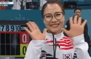 a woman wearing glasses is smiling in front of a scoreboard that says 7891