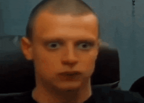 a man with a shaved head is looking at the camera .