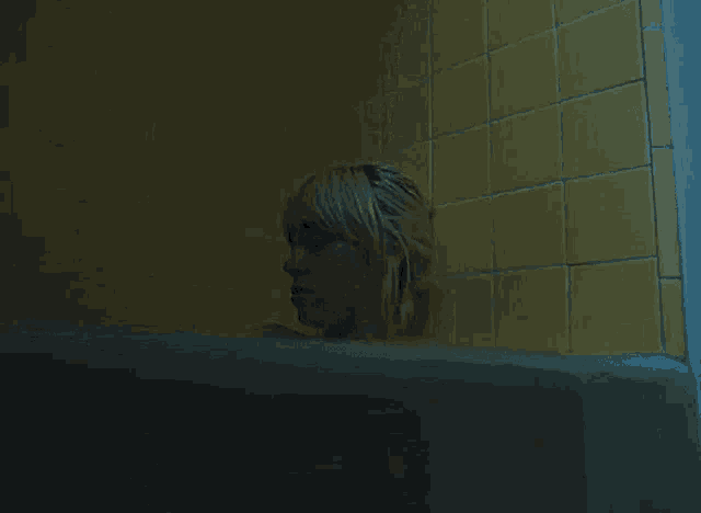 a woman is sitting in a bathtub in a dark bathroom .