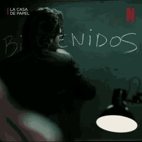 a man in a suit and tie is standing in front of a chalkboard that says bienvenidos .