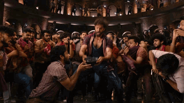a man in a blue tank top is surrounded by people