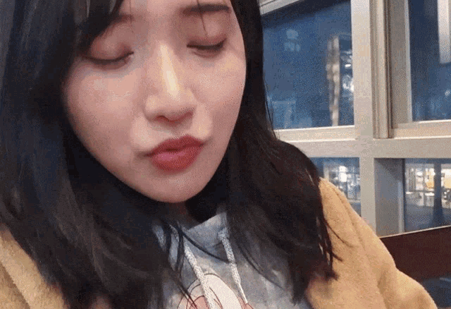 a close up of a woman 's face with her eyes closed and a window in the background