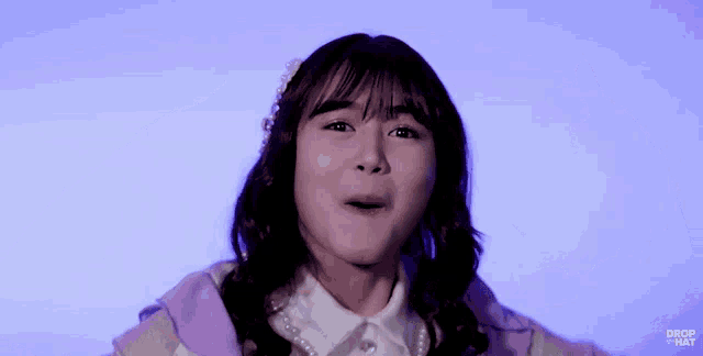 a young girl is making a funny face while wearing a purple jacket .
