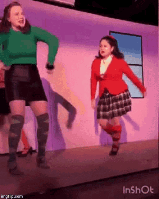 a couple of women are dancing on a stage in a room .