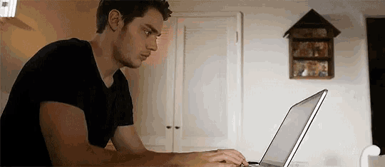 a man is using a laptop computer in a kitchen .