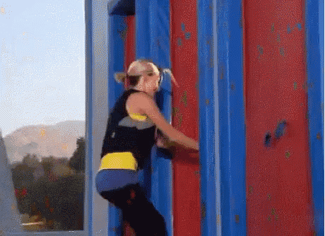 a woman is climbing up a blue and red wall
