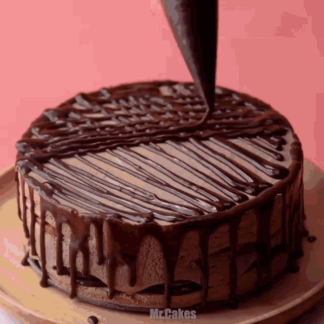 a chocolate cake is being decorated with chocolate icing by mr.cakes