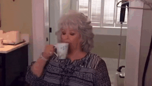 a woman is drinking a cup of coffee in a room .