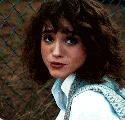 a close up of a woman 's face against a chain link fence