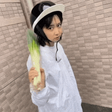 a girl wearing a helmet and holding a green vegetable