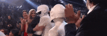a group of people are standing next to each other in a crowd and applauding a robot .
