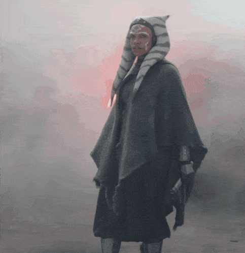 a woman wearing a striped hat and a poncho stands in the fog