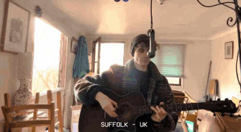 a man playing a guitar in a room with the word suffolk on the bottom right