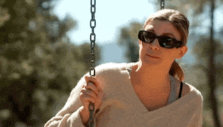 a woman is sitting on a swing wearing sunglasses .