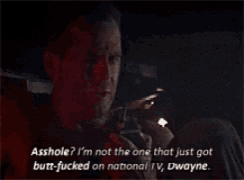 a man is talking on a cell phone in a dark room and says asshole