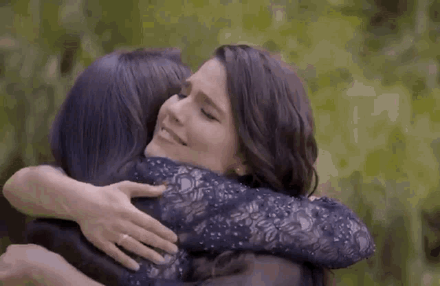 two women hugging each other with one wearing a blue dress