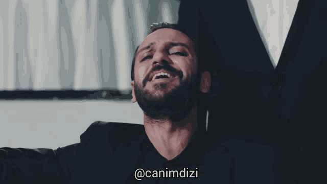 a man with a beard is smiling with the hashtag @canimdizi behind him
